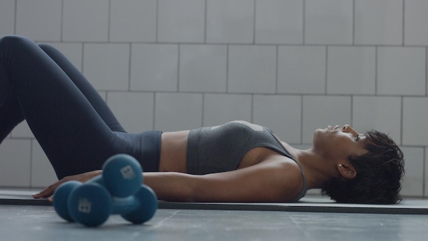 Zijaanzicht van zwarte vrouw maakt een buikspieroefening op de vloer i synny loft Helthy fitness workout routine