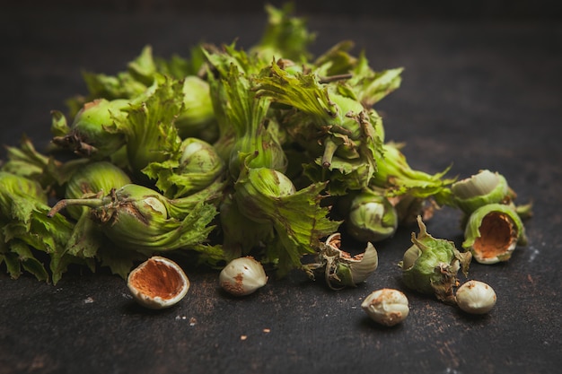 Zijaanzicht verse groene hazelnoten op donkerbruin.