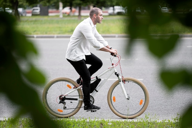 Gratis foto zijaanzicht volwassen mannelijke fiets op straat