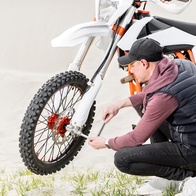 Gratis foto zijaanzicht volwassen mannetje dat motor probeert te herstellen