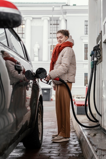 Zijaanzicht vrouw bij benzinestation