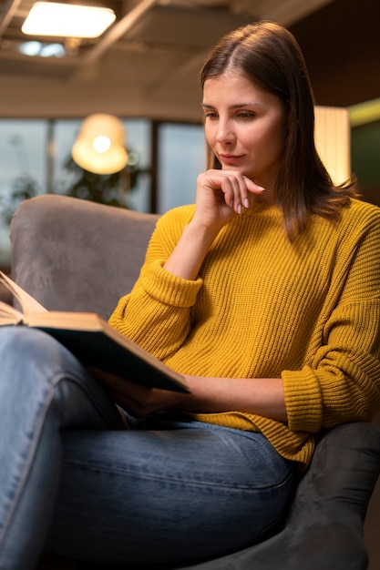 Gratis foto zijaanzicht vrouw die binnen leest