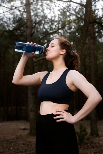 Gratis foto zijaanzicht vrouw drinkwater