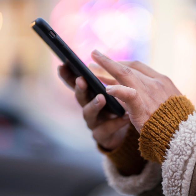 Gratis foto zijaanzicht vrouw haar telefoon buitenshuis controleren