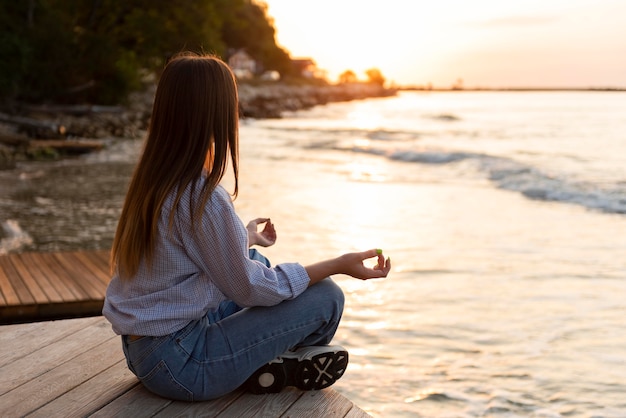 Zijaanzicht vrouw kijken naar de zee bij zonsondergang met kopie ruimte