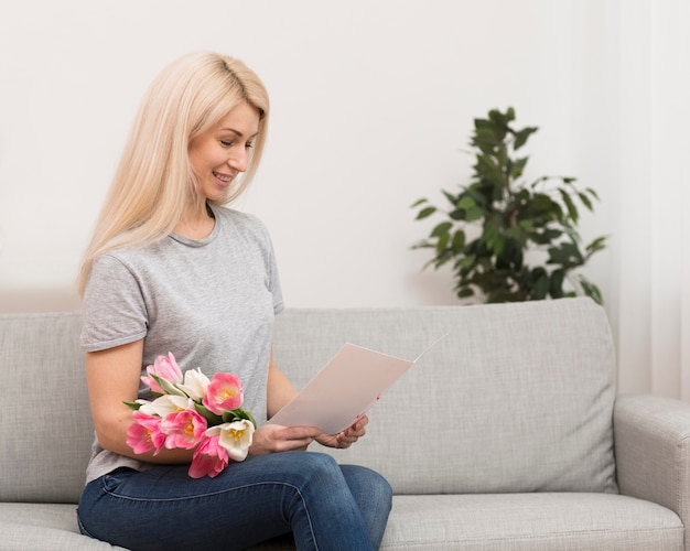 Gratis foto zijaanzicht vrouw leest wenskaart