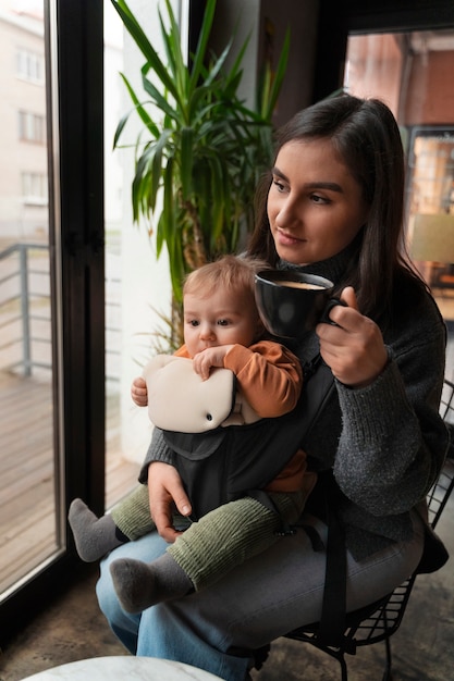 Gratis foto zijaanzicht vrouw met baby in draagzak