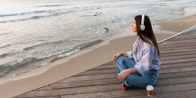 Zijaanzicht vrouw zittend naast het strand met kopie ruimte