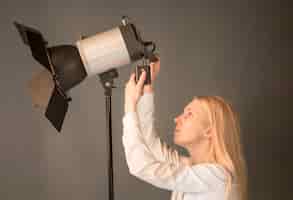 Gratis foto zijaanzicht vrouwelijke fotograaf die de lamp aanpast
