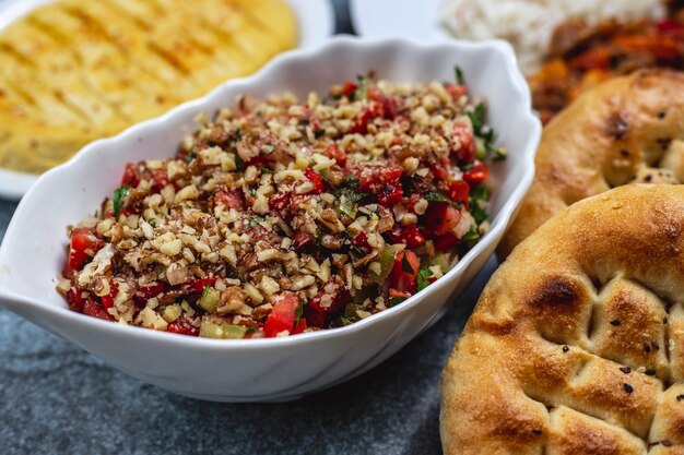 Zijaanzicht walnoot salade met tomaten komkommer greens en brood op tafel