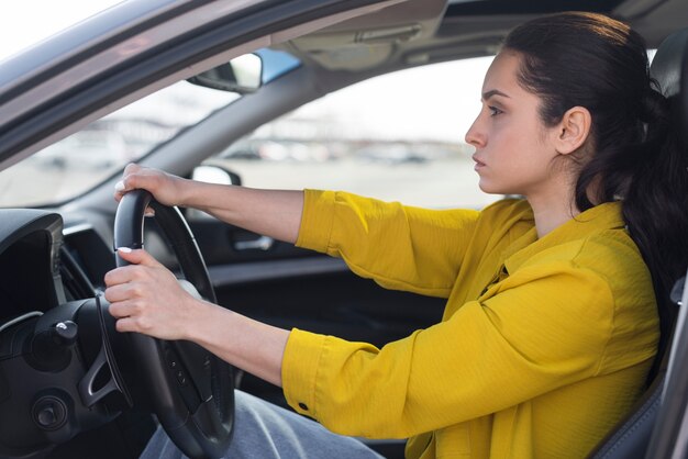 Zijaanzicht zekere vrouw die haar auto drijft