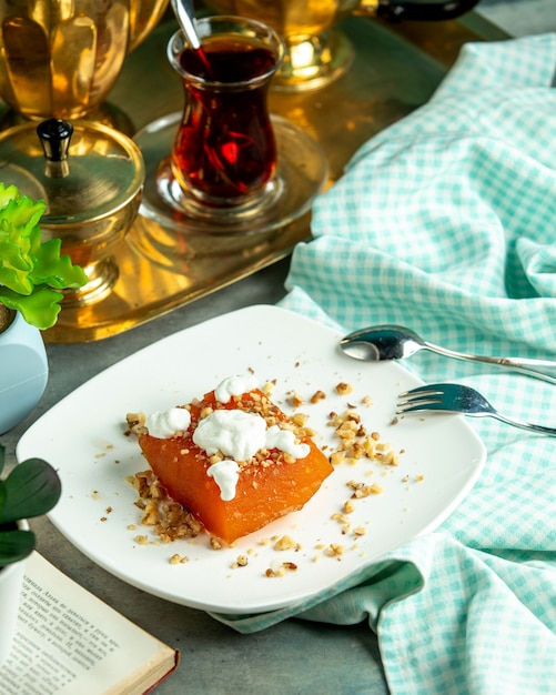 Zijaanzicht zoete pompoen met room en noten en een glas thee