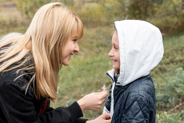 Zijaanzicht zorgvuldige vrouw schikken dochter jas