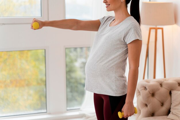 Zijaanzicht zwangere vrouw training met gewichten