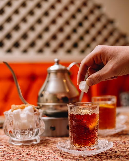 Zijaanzicht zwarte thee met schijfje citroen snoep en theepot op tafel