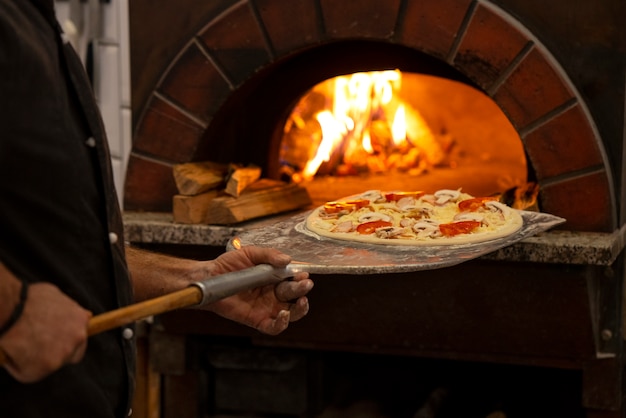 Zijaanzichtchef-kok die heerlijke pizza bakt