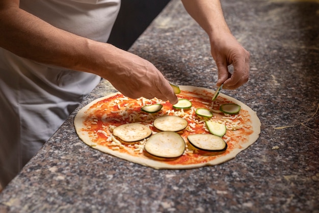 Zijaanzichtchef-kok die pizza voorbereidt