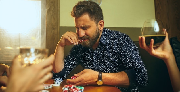 Gratis foto zijaanzichtfoto van vrienden die aan houten tafel zitten. vrienden hebben plezier tijdens het spelen van bordspel.