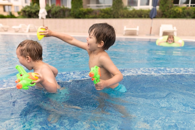 Zijaanzichtjongens die bij pool spelen