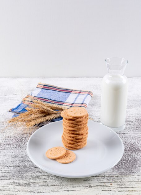 Zijaanzichtkoekjes met melk op witte houten lijst en witte verticaal 2 als achtergrond