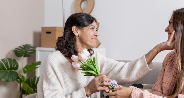 Zijaanzichtmeisje die bloemen aanbieden aan mamma