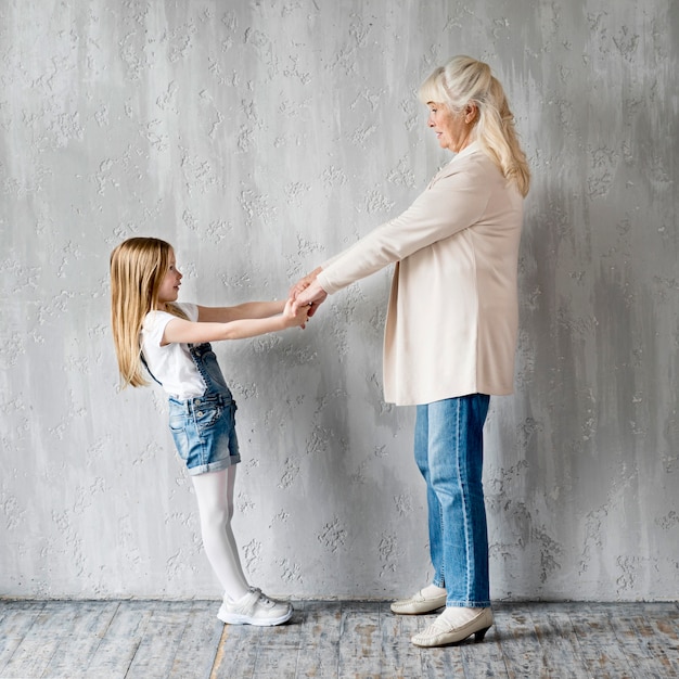 Zijaanzichtmeisje en oma hand in hand