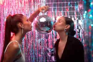 Gratis foto zijaanzichtmeisjes die discobal kussen