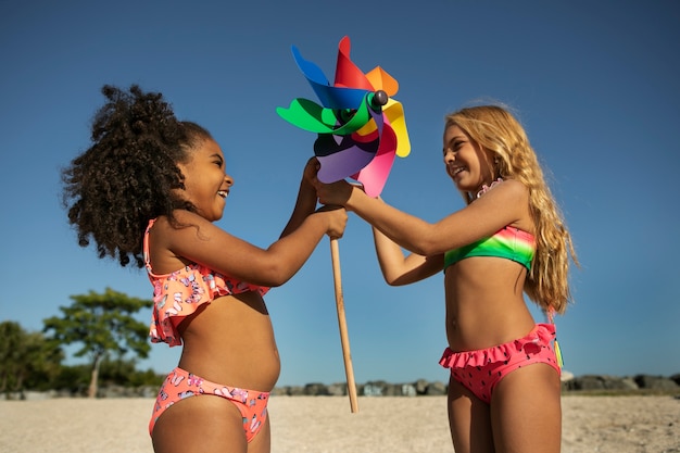 Gratis foto zijaanzichtmeisjes die samen op strand spelen