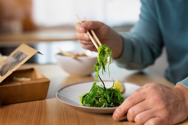 Gratis foto zijaanzichtmens die aziatisch voedsel eet