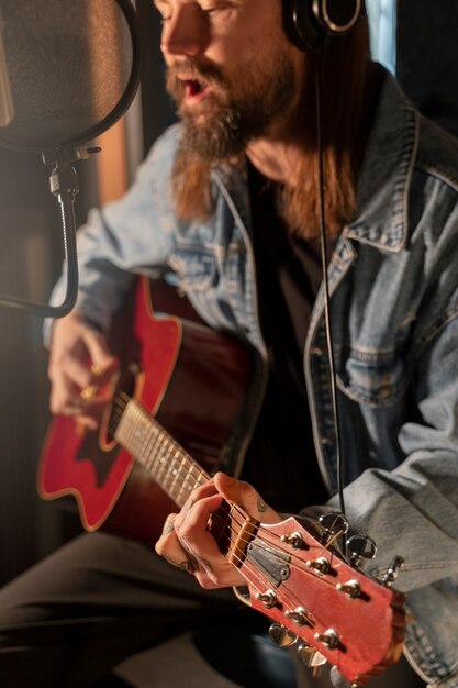 Zijaanzichtmens die de gitaar in studio speelt