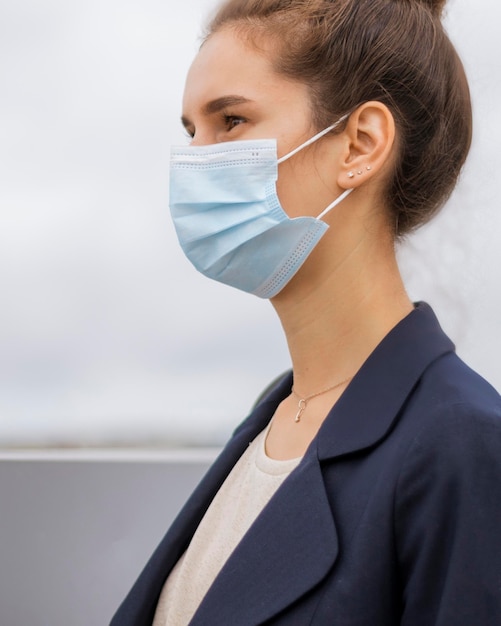 Gratis foto zijaanzichtonderneemster die een medisch masker draagt