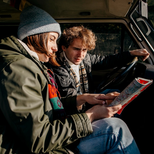 Gratis foto zijaanzichtpaar dat een kaart bekijkt terwijl over de weg struikelt