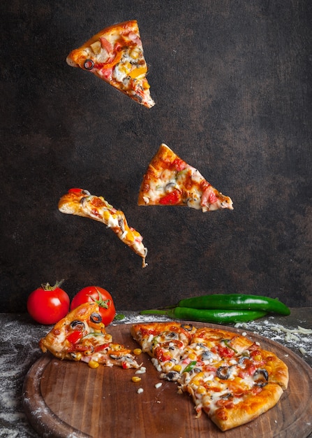 Gratis foto zijaanzichtpizza met peper en tomaat en pizzaplakken in raadskookgerei