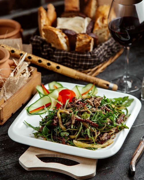 Zijaanzichtsalade met greens en vlees met groenten op een raad met brood