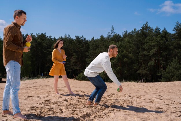 Zijaanzichtvrienden die een spel spelen op het strand