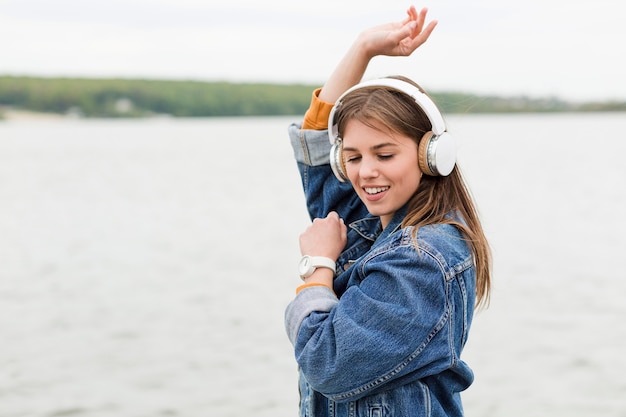 Zijaanzichtvrouw die bij het luisteren muziek dansen