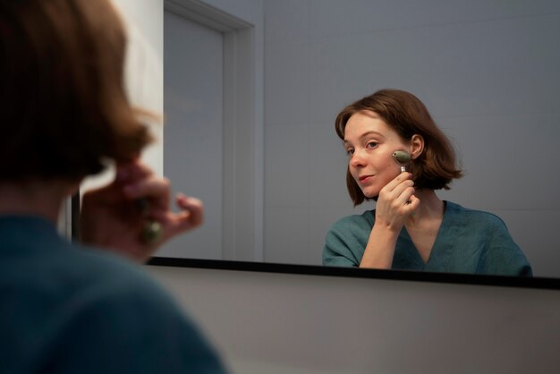 Zijaanzichtvrouw die gezichtsrol gebruiken voor massage