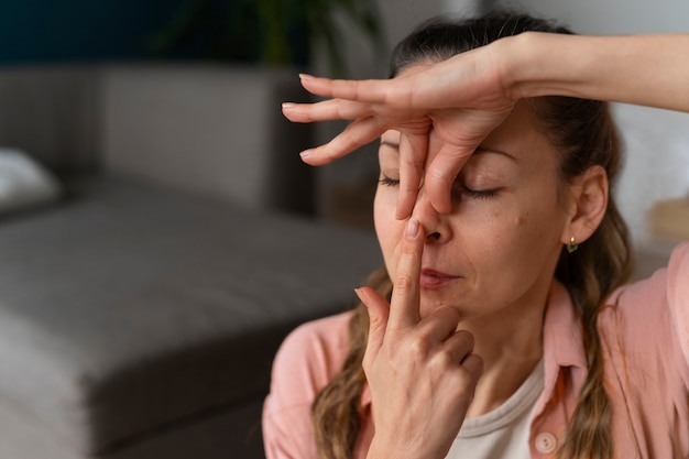 Gratis foto zijaanzichtvrouw die gezichtsyoga beoefent