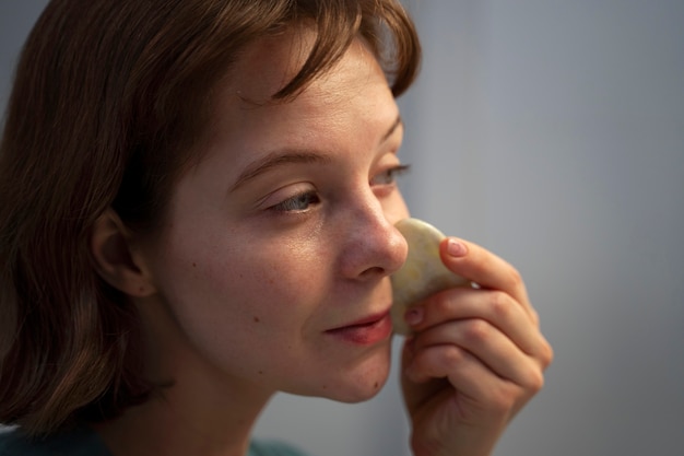 Zijaanzichtvrouw die gua sha gebruiken voor massage