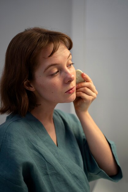 Zijaanzichtvrouw die gua sha gebruiken voor massage