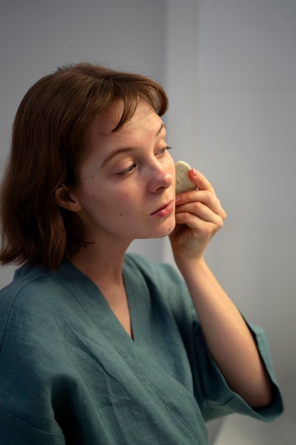 Zijaanzichtvrouw die gua sha gebruiken voor massage