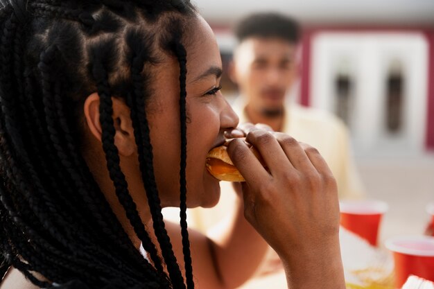 Zijaanzichtvrouw die hamburger buitenshuis eet