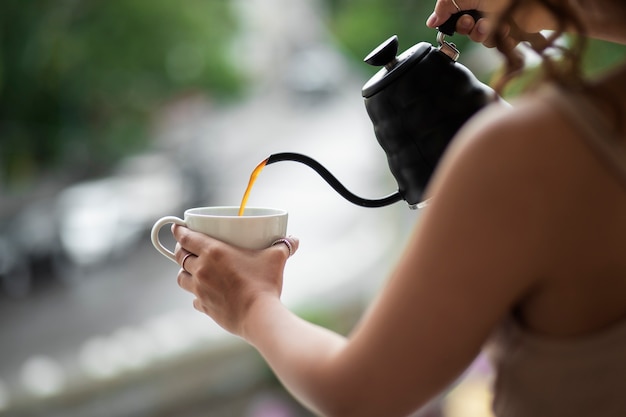 Gratis foto zijaanzichtvrouw die koffie schenkt