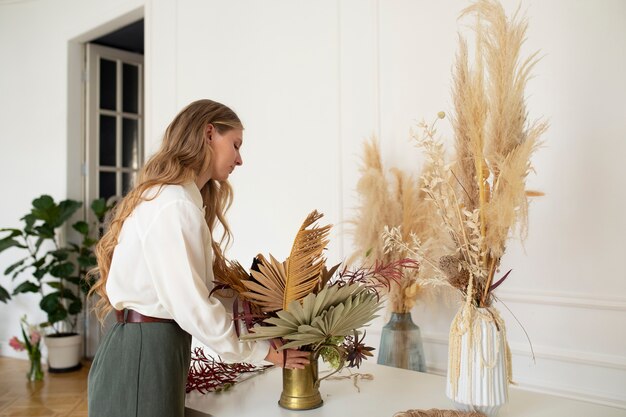 Zijaanzichtvrouw die met droogbloemen werkt