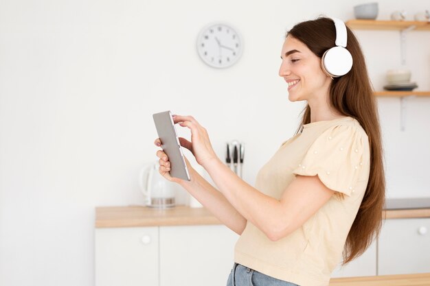 Zijaanzichtvrouw die met hoofdtelefoons een lied van haar laptop kiest