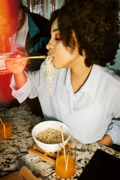 Zijaanzichtvrouw die noedels eet