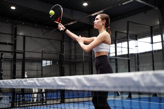 Zijaanzichtvrouw die paddletennis speelt