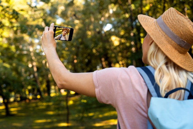 Gratis foto zijaanzichtvrouw die selfie met telefoon neemt