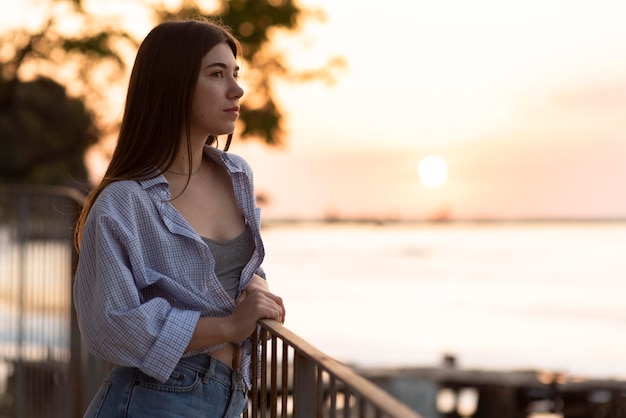 Zijaanzichtvrouw die weg bij zonsondergang kijken