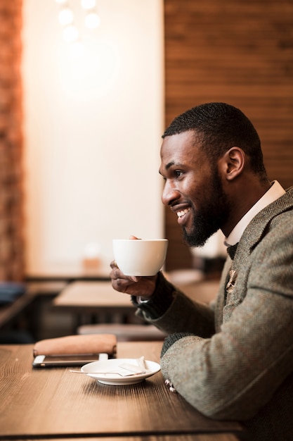 Zijdelings knappe mens die een kop met koffie houdt